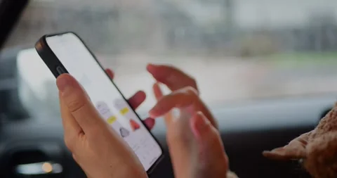 Close-up of hands browsing on a smartphone inside a car, against a rainy... Stock Footage 319882124