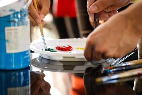 Close-up of hands with brushes mixing paints on a palette at a workshop Stock Photos