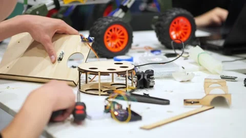 Close-up of hands building a robot from wooden pieces and electronics Stock Footage 344979870