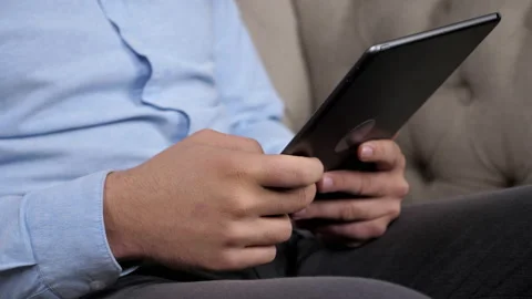 Close up hands businessman uses tablet sitting on couch at home office Stock Footage 167017457