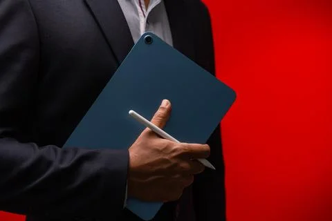 Close up hands of businessman using digital tablet device isolated on red b.. Stock Photos