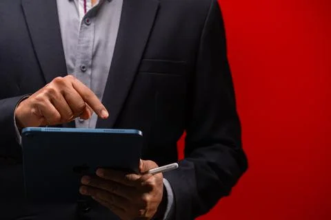Close up hands of businessman using digital tablet device isolated on red b.. Foto stock