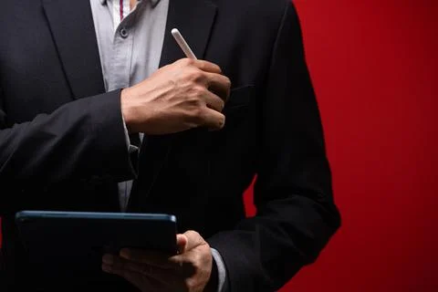 Close up hands of businessman using digital tablet device isolated on red b.. Foto stock
