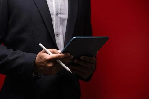 Close up hands of businessman using digital tablet device isolated on red b.. Stock Photos