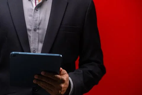 Close up hands of businessman using digital tablet device isolated on red b.. Foto stock