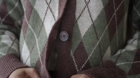Close up of hands buttoning argyle pattern cardigan, slow motion, cozy knit.. 库存影片 332884791