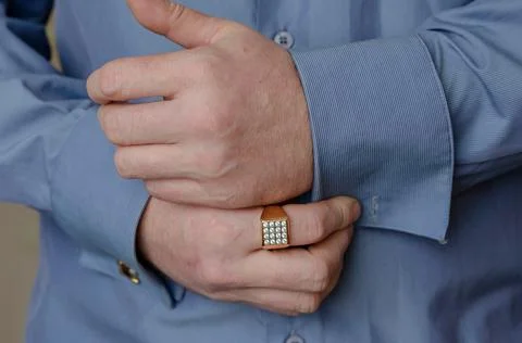 Close-up of hands buttoning a cufflink on the sleeve of a blue shirt. A middl Stock Photos