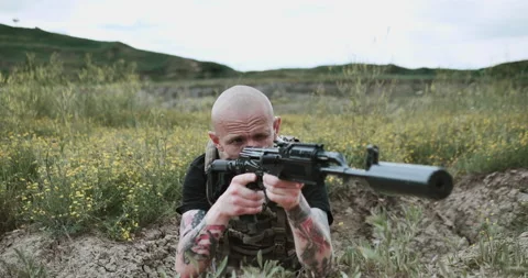 Close-up of the hands of a camouflaged man loading bullets into a rifle chamber Stock Footage 134388508