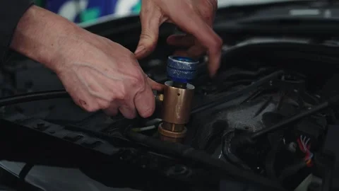 Close-up hands of a car master using a machine to refill a car air conditioner Stock Footage 285642994