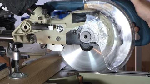 Close-up. Hands of a carpenter lower a circular saw on a wooden block. Slow Stock Footage 113996659