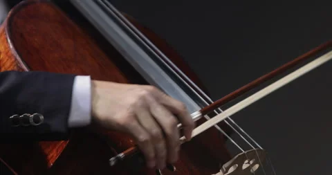 Close-up of the hands of a cellist holding a bow, performing a piece of music on Stock Footage 248216654