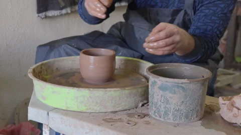 Close up hands of a ceramist using potter's wheel to make a cup Stock Footage 240636554
