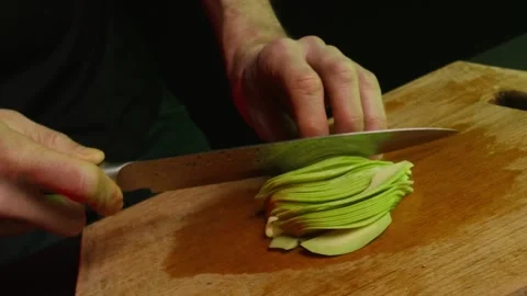 Close up hands of chef cook slicing avocado in slow motion in a dark kitchen Video stock 153206666