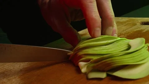 Close up hands of chef cook slicing avocado in slow motion in a dark kitchen Video stock 153206752