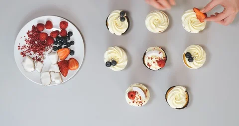 Close-up hands of chef decorating cupcakes with colored berries Stock Footage 129326896