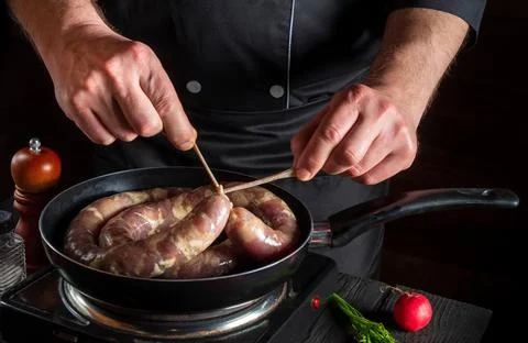 Close-up hands of chef or cook tying a thread of homemade sausage. Cooking Stock Photos