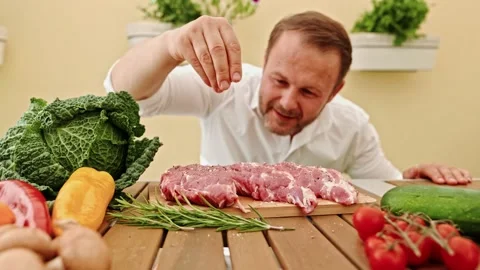 Close-up with the hands of the chef salting the steak and pressing it before Video stock 201139900