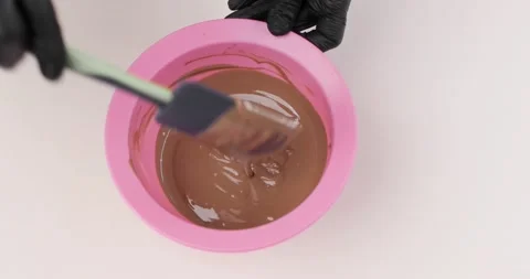 Close-up hands of a chef stirring chocolate or chocolate cream in a bowl with a Vídeo Stock 165578912