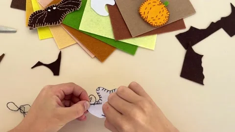 Close-up of the hands of a child who makes decorative garland for Halloween Stock Footage 213674944