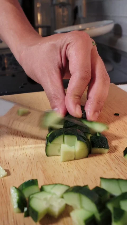Close-up of hands chopping fresh green cucumber into cubes for salad Stock Footage 346773844