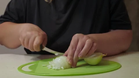 Close-up hands chopping peeled onion on green cutting board Vidéo 342361635