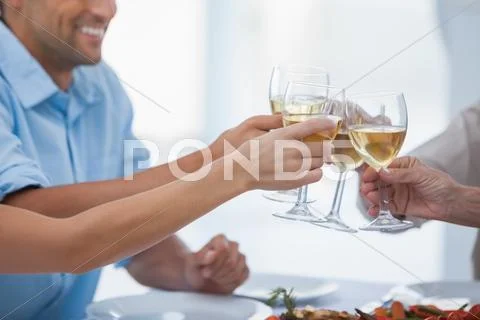 Close up of hands clinking glasses of white wine Stock Photos