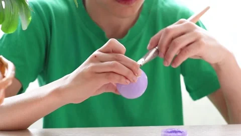 Close-up of hands coloring a chicken egg in purple. Preparation for Easter Stock Footage 173548906