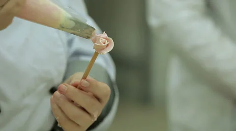 Close up of hands of confectioner doing cream rose flower for cake decorating. Stock Footage 50476036