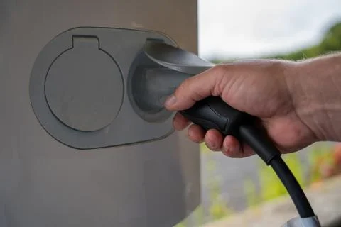 Close-up of hands connecting cables to an electric vehicle charger Stock Photos
