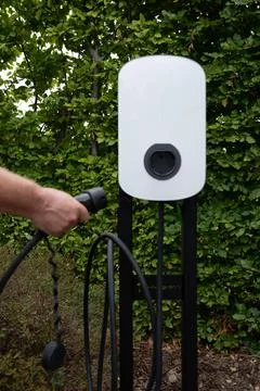 Close-up of hands connecting cables to an electric vehicle charger Stock Photos