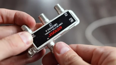 Close-up of hands connecting coaxial cables to a 3-way splitter, plugging IN Stockbeeldmateriaal 312357818