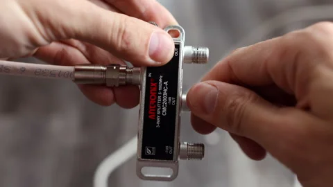 Close-up of hands connecting coaxial cables to a 3-way splitter Stockbeeldmateriaal 312357901