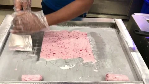 Close-up, hands of a cook in gloves roll Thai ice cream on a metal frying pan Stock Footage 310395939