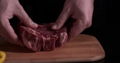 Close-up hands cook prepares meat for cooking on a black background Stock Footage 130360186