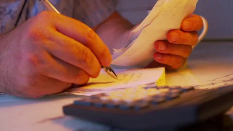 Close-up of hands copying receipt data into a financial notebook Stock Footage 336979107