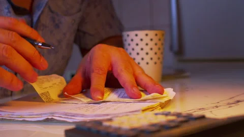Close-up of hands copying receipt data into a financial notebook Stock Footage 336982273