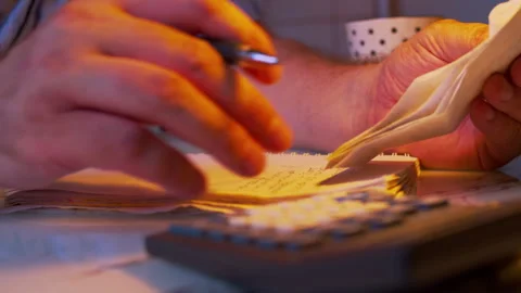 Close-up of hands copying receipt data into a financial notebook Stock Footage 336989110