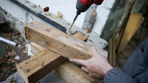 Close up of hands with cordless drill, twisting a screw into a wooden prisms Stock Footage 158977421