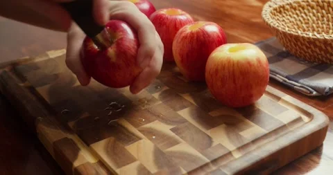 Close-up of hands coring fresh red apples on a wooden cutting board as they Stock Footage 319383858