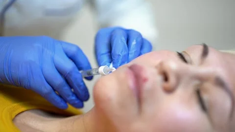 Close up of hands of cosmetologist making botox injection. She is holding Stock Footage 145695010
