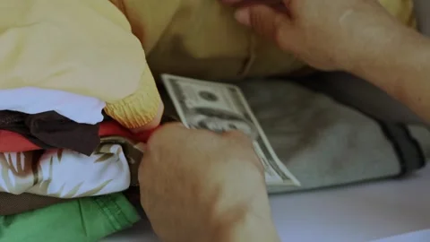 Close-up of hands counting dollar bills and hiding them among folded clothes. Stock Footage 313610928