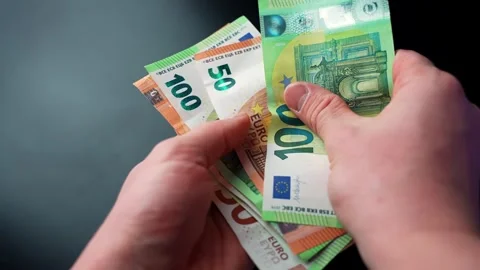 Close-up of hands counting euro banknotes (50 and 100) against a dark Stock Footage 328587565