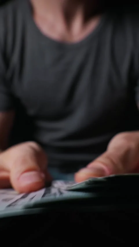 Close Up of Hands Counting Large Stack of Dollar Bills in Low Light Stock Footage 339366686