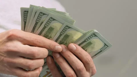 Close up of hands counting a large stack of US dollar bills, symbolizing Video stock 341038015
