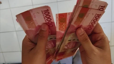 Close up of hands counting stack of Indonesian Rupiah 100,000 banknotes. Stock Footage 336584664