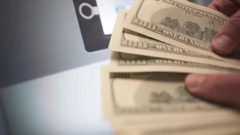 Close-up of hands counting US dollar bills in front of an ATM. Vídeos de archivo 337710704