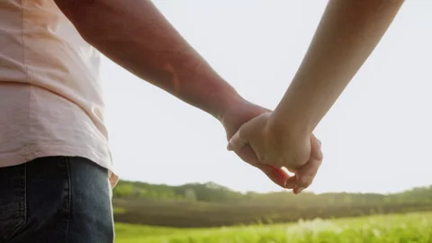 Close-up of the hands of a couple holding hands outside in a plain place. Love Stock Footage 243545367