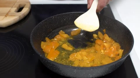A close-up of hands cracking eggs into a skillet with chopped vegetables. The Stock Footage 336445883