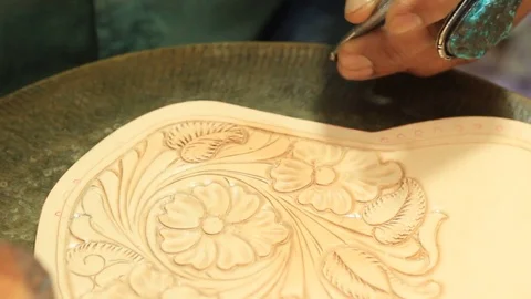 Close up of the hands of a craftsman stamping a design in leather Stock Footage 100798328