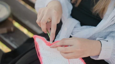 Close up hands crocheting pink fabric with green hook detailed textile project Stock Footage 345130865